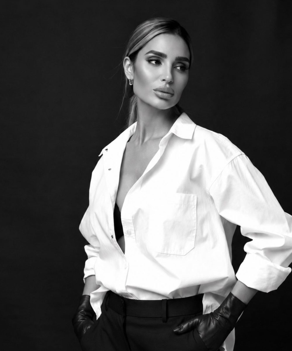 Racheli Asban in a white shirt and black gloves, black-and-white portrait
